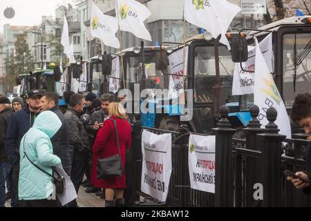 Traktoren ukrainischer Bauern mit Plakaten mit der Aufschrift „Nein zum Verkauf ukrainischen Landes!“ Werden vor dem Parlament geparkt, während einige hundert Menschen gegen die eventuelle Annahme des Grundmarktgesetzes vor Werchowna Rada in Kiew, Ukraine, am 13. November 2019 protestieren. In der Nähe des ukrainischen Parlamentsgebäudes findet eine Kundgebung statt, die von Gegnern des Landmarktes abgehalten wird. Der ukrainische Präsident Zelensky sagte in einer am 11. November 2019 veröffentlichten Videoansprache an die Nation, dass die Frage des Verkaufs von Ackerland an Ausländer und von Ausländern gegründete Unternehmen einer All-Ukrainerin vorgelegt wird Stockfoto