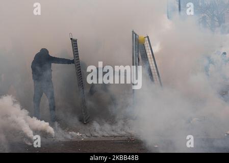 Demonstranten aus dem Schwarzen Block Zuflucht hinter einer Barrikade aus Baubarrieren, die sie als Schild verwenden, um die Polizei, die mit Tränengas replizieren, an diesem Samstag, dem 16. November 2019, während fand in Paris die Jubiläumsveranstaltung Gelbe Westen für 1 Jahr der Bewegung. Eine große Demonstration sollte zwischen dem Place d'Italie und dem Gare du Nord stattfinden, aber nach Szenen der Gewalt zwischen dem Schwarzen Block und der Polizei, hat die Präfektur den marsch abgesagt, der Szenen des Chaos Platz machte. (Foto von Samuel Boivin/NurPhoto) Stockfoto