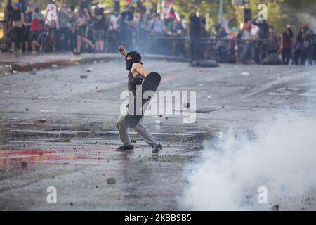 Ein regierungsfeindlicher Demonstrator fordert bei Zusammenstößen mit der Polizei in Santiago, Chile, am Donnerstag, 30. Oktober 2019, einen Wasserkanonenstrahl der Polizei heraus. (Foto von Jeremias Gonzalez/NurPhoto) Stockfoto