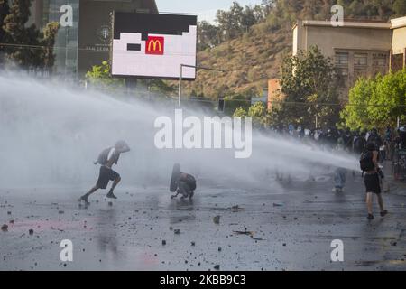 Ein regierungsfeindlicher Demonstrator fordert bei Zusammenstößen mit der Polizei in Santiago, Chile, am Donnerstag, 30. Oktober 2019, einen Wasserkanonenstrahl der Polizei heraus. (Foto von Jeremias Gonzalez/NurPhoto) Stockfoto