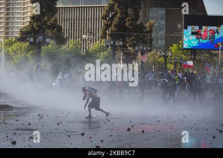 Ein regierungsfeindlicher Demonstrator fordert bei Zusammenstößen mit der Polizei in Santiago, Chile, am Donnerstag, 30. Oktober 2019, einen Wasserkanonenstrahl der Polizei heraus. (Foto von Jeremias Gonzalez/NurPhoto) Stockfoto