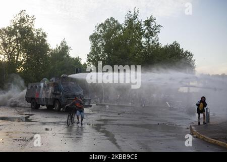 Ein regierungsfeindlicher Demonstrator fordert bei Zusammenstößen mit der Polizei in Santiago, Chile, am Donnerstag, 30. Oktober 2019, einen Wasserkanonenstrahl der Polizei heraus. (Foto von Jeremias Gonzalez/NurPhoto) Stockfoto