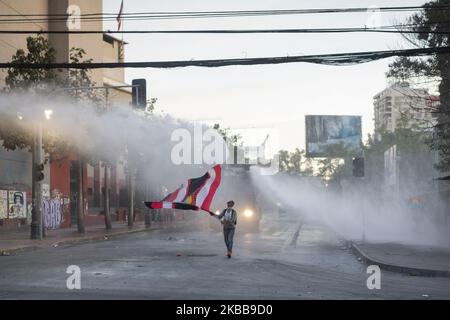 Ein regierungsfeindlicher Demonstrator fordert bei Zusammenstößen mit der Polizei in Santiago, Chile, am Donnerstag, 30. Oktober 2019, einen Wasserkanonenstrahl der Polizei heraus. (Foto von Jeremias Gonzalez/NurPhoto) Stockfoto