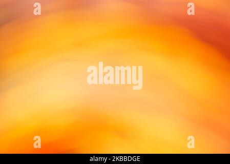 Künstlerisch abstrakter warmer Hintergrund in kräftigen Orange- und Gelbtönen. Geschmeidiges und fließendes Design, modern und lebendig. Stockfoto