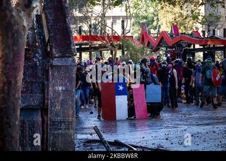 Demonstranten schützen sich am 26. November 2019 bei einem Protest gegen die Regierung von Präsident Sebastian Pinera in Santiago de Chile vor Wasser. Mehr als 40 Tage dauern die Konflikte und Demonstrationen in Santiago de Chile, der Hauptstadt Chiles, an. Der Protest ist gegen die Politik ihres Präsidenten Sebastian Pinera.(Foto: Federico Rotter/NurPhoto) Stockfoto