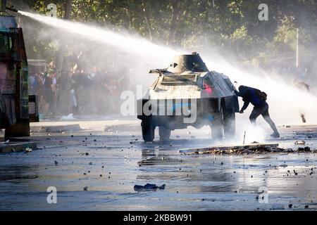 Demonstranten schützen sich am 26. November 2019 bei einem Protest gegen die Regierung von Präsident Sebastian Pinera in Santiago de Chile vor Wasser. Mehr als 40 Tage dauern die Konflikte und Demonstrationen in Santiago de Chile, der Hauptstadt Chiles, an. Der Protest ist gegen die Politik ihres Präsidenten Sebastian Pinera.(Foto: Federico Rotter/NurPhoto) Stockfoto