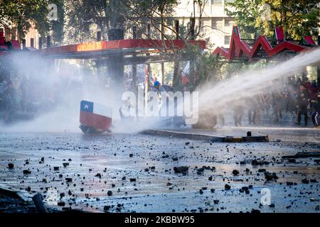 Demonstranten schützen sich am 26. November 2019 bei einem Protest gegen die Regierung von Präsident Sebastian Pinera in Santiago de Chile vor Wasser. Mehr als 40 Tage dauern die Konflikte und Demonstrationen in Santiago de Chile, der Hauptstadt Chiles, an. Der Protest ist gegen die Politik ihres Präsidenten Sebastian Pinera.(Foto: Federico Rotter/NurPhoto) Stockfoto