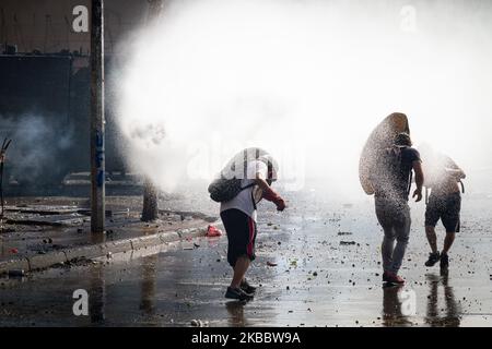 Demonstranten schützen sich am 26. November 2019 bei einem Protest gegen die Regierung von Präsident Sebastian Pinera in Santiago de Chile vor Wasser. Mehr als 40 Tage dauern die Konflikte und Demonstrationen in Santiago de Chile, der Hauptstadt Chiles, an. Der Protest ist gegen die Politik ihres Präsidenten Sebastian Pinera.(Foto: Federico Rotter/NurPhoto) Stockfoto