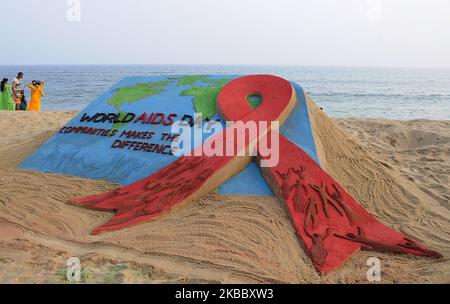 Eine Awareness-Sandskulptur ist am östlichen Küstenstrand der Bucht von Bengalen zu sehen, wie sie vom Sandkünstler Manas Sahoo für Besucher geschaffen wird, die sich über den Welt-Aids-Tag informieren, der 65 km von der ostindischen Hauptstadt Bhubaneswar des Staates Odisha entfernt ist. (Foto von STR/NurPhoto) Stockfoto