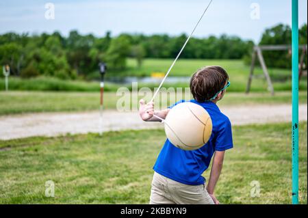 Tetherball wird in einem Spiel mit einem kleinen Jungen getroffen und umgeseilt. Stockfoto