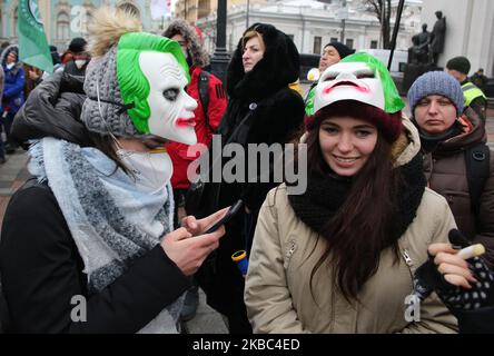 Menschen mit Atemschutzmasken und den Masken von Joker halten die Plakate mit der Aufschrift „Rettet Einzelunternehmer“ auf der Werchowna Rada in Kiew, Ukraine, 3. Dezember 2019. Einige hundert Einzelunternehmer protestieren vor dem ukrainischen Parlament mit der Forderung, das Gesetz abzuschaffen, was nach Ansicht der Demonstranten zur Zerstörung des vereinfachten Systems der Besteuerung, Rechnungslegung und Berichterstattung führen wird. (Foto von Sergii Chartschenko/NurPhoto) Stockfoto