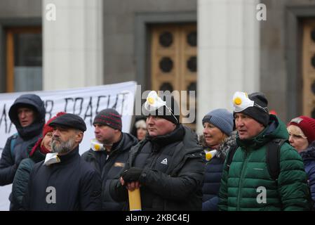 Menschen mit Atemschutzmasken und den Masken von Joker halten die Plakate mit der Aufschrift „Rettet Einzelunternehmer“ auf der Werchowna Rada in Kiew, Ukraine, 3. Dezember 2019. Einige hundert Einzelunternehmer protestieren vor dem ukrainischen Parlament mit der Forderung, das Gesetz abzuschaffen, was nach Ansicht der Demonstranten zur Zerstörung des vereinfachten Systems der Besteuerung, Rechnungslegung und Berichterstattung führen wird. (Foto von Sergii Chartschenko/NurPhoto) Stockfoto