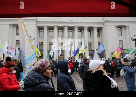 Menschen mit Atemschutzmasken und den Masken von Joker halten die Plakate mit der Aufschrift „Rettet Einzelunternehmer“ auf der Werchowna Rada in Kiew, Ukraine, 3. Dezember 2019. Einige hundert Einzelunternehmer protestieren vor dem ukrainischen Parlament mit der Forderung, das Gesetz abzuschaffen, was nach Ansicht der Demonstranten zur Zerstörung des vereinfachten Systems der Besteuerung, Rechnungslegung und Berichterstattung führen wird. (Foto von Sergii Chartschenko/NurPhoto) Stockfoto