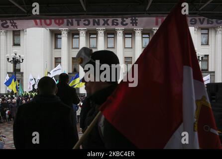 Menschen mit Atemschutzmasken und den Masken von Joker halten die Plakate mit der Aufschrift „Rettet Einzelunternehmer“ auf der Werchowna Rada in Kiew, Ukraine, 3. Dezember 2019. Einige hundert Einzelunternehmer protestieren vor dem ukrainischen Parlament mit der Forderung, das Gesetz abzuschaffen, was nach Ansicht der Demonstranten zur Zerstörung des vereinfachten Systems der Besteuerung, Rechnungslegung und Berichterstattung führen wird. (Foto von Sergii Chartschenko/NurPhoto) Stockfoto