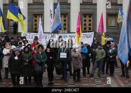 Menschen mit Atemschutzmasken und den Masken von Joker halten die Plakate mit der Aufschrift „Rettet Einzelunternehmer“ auf der Werchowna Rada in Kiew, Ukraine, 3. Dezember 2019. Einige hundert Einzelunternehmer protestieren vor dem ukrainischen Parlament mit der Forderung, das Gesetz abzuschaffen, was nach Ansicht der Demonstranten zur Zerstörung des vereinfachten Systems der Besteuerung, Rechnungslegung und Berichterstattung führen wird. (Foto von Sergii Chartschenko/NurPhoto) Stockfoto