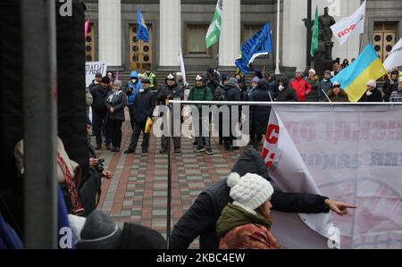 Menschen mit Atemschutzmasken und den Masken von Joker halten die Plakate mit der Aufschrift „Rettet Einzelunternehmer“ auf der Werchowna Rada in Kiew, Ukraine, 3. Dezember 2019. Einige hundert Einzelunternehmer protestieren vor dem ukrainischen Parlament mit der Forderung, das Gesetz abzuschaffen, was nach Ansicht der Demonstranten zur Zerstörung des vereinfachten Systems der Besteuerung, Rechnungslegung und Berichterstattung führen wird. (Foto von Sergii Chartschenko/NurPhoto) Stockfoto