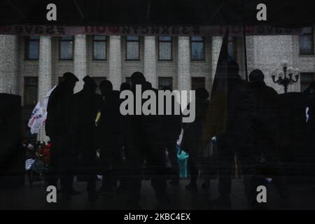 Menschen mit Atemschutzmasken und den Masken von Joker halten die Plakate mit der Aufschrift „Rettet Einzelunternehmer“ auf der Werchowna Rada in Kiew, Ukraine, 3. Dezember 2019. Einige hundert Einzelunternehmer protestieren vor dem ukrainischen Parlament mit der Forderung, das Gesetz abzuschaffen, was nach Ansicht der Demonstranten zur Zerstörung des vereinfachten Systems der Besteuerung, Rechnungslegung und Berichterstattung führen wird. (Foto von Sergii Chartschenko/NurPhoto) Stockfoto