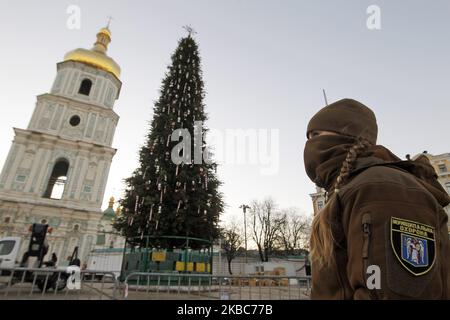 Am 05. Dezember 2019 steht auf dem Sophia-Platz in Kiew, Ukraine, ein Mitglied der kommunalen Sicherheitskräfte neben dem Hauptweihnachtbaum. Der wichtigste ukrainische Weihnachtsbaum von 30 Metern Höhe und einem Gewicht von 100 Tonnen wird mit 750 Süßigkeiten Spielzeug und 4 Kilometer Girlanden geschmückt. Die Charaktere aus dem Ballett "Nussknacker" und ukrainischen Märchen werden es umbringen. Der Weihnachtsbaum wird am 19. Dezember 2019 am Nikolaustag angezündet. (Foto von STR/NurPhoto) Stockfoto