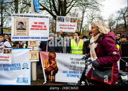 Eine Frau kommt mit ihrem Fahrrad vor einer Gruppe von Menschen, die Rohingya unterstützen, während einer Solidaritätskundgebung der Rohingya vor dem Internationalen Gerichtshof in Den Haag am 11.. Dezember 2019 vorbei. (Foto von Romy Arroyo Fernandez/NurPhoto) Stockfoto