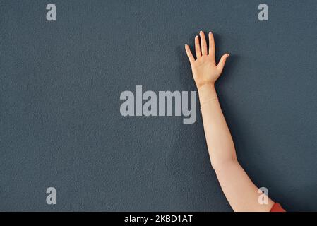 Ich möchte etwas sagen. Studioaufnahme einer unkenntlichen Frau, die ihre Hand vor einem grauen Hintergrund hebt. Stockfoto