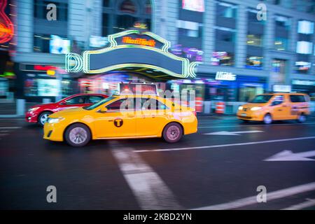 Ikonisches gelbes Taxi auf den Straßen von Midtown Manhattan, New York City nahe Times Square, 7. Ave und Broadway Avenue am 18. November 2019 in New York, USA. Beleuchtung und Nachtlichter des sich bewegenden Verkehrs von Fahrzeugen, Autos und stationären Taxis. (Foto von Nicolas Economou/NurPhoto) Stockfoto