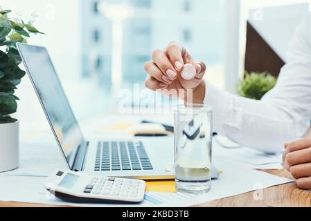 Dieses Vitamin ist genau das, was er braucht. Ein nicht erkennbarer Geschäftsmann, der eine Brausetablette in einem Glas Wasser auflöst. Stockfoto