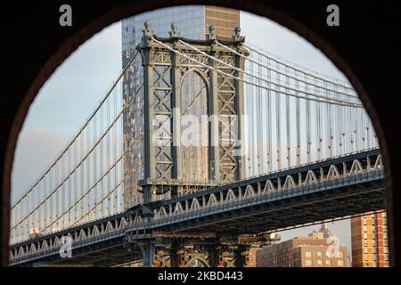 Am frühen Morgen Blick auf die ikonische Manhattan Bridge aus der Sicht des Dumbo Viertels in Brooklyn, NYC, USA am 14. November 2019. Die 448m. Lange Hängebrücke ist ein Wahrzeichen der Stadt New York, eine Touristenattraktion, die den East River überquert und Lower Manhattan mit der Innenstadt von Brooklyn verbindet. Die metallische Eisenbrücke ist aktiv mit Verkehr, 7 Fahrspuren und 4 Bahngleisen für die U-Bahn und Fahrräder. Es wurde 1909 von der Phoenix Bridge Company für den Verkehr geöffnet und von Leon Moisseiff entworfen. (Foto von Nicolas Economou/NurPhoto) Stockfoto