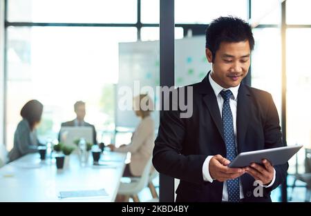 Ein hübscher junger Geschäftsmann, der ein Tablet am Arbeitsplatz verwendet. Stockfoto