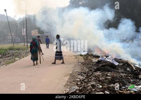 Am 18. Dezember 2019 brennen in einem Park in Dhaka, Bangladesch, Menschen, die zu Fuß den Müll verbrennen. Bangladesch, eines der am dichtesten besiedelten Länder der Welt, kämpft seit langem mit der Luftverschmutzung, während Dhaka weiterhin zu den am stärksten verschmutzten Städten zählt. Die Hauptquellen der Verschmutzung sind laut der Studie feste Brennstoffe aus dem Haushalt, Baustaub, Kohlekraftwerke, Ziegelproduktion, Transport und dieselbetriebene Geräte unter anderem. Die Luftqualität in Asien blieb hartnäckig schlecht; vor allem in Bangladesch, wo die gesamte Bevölkerung h Stockfoto