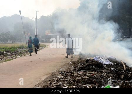 Am 18. Dezember 2019 brennen in einem Park in Dhaka, Bangladesch, Menschen, die zu Fuß den Müll verbrennen. Bangladesch, eines der am dichtesten besiedelten Länder der Welt, kämpft seit langem mit der Luftverschmutzung, während Dhaka weiterhin zu den am stärksten verschmutzten Städten zählt. Die Hauptquellen der Verschmutzung sind laut der Studie feste Brennstoffe aus dem Haushalt, Baustaub, Kohlekraftwerke, Ziegelproduktion, Transport und dieselbetriebene Geräte unter anderem. Die Luftqualität in Asien blieb hartnäckig schlecht; vor allem in Bangladesch, wo die gesamte Bevölkerung h Stockfoto