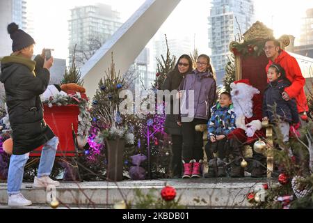 Am 21. Dezember 2019 posieren Menschen auf dem Toronto Christmas Market auf dem Nathan Philips Square in Toronto, Ontario, Kanada, für ein Foto mit einem Mann, der als Weihnachtsmann gekleidet ist. (Foto von Creative Touch Imaging Ltd./NurPhoto) Stockfoto