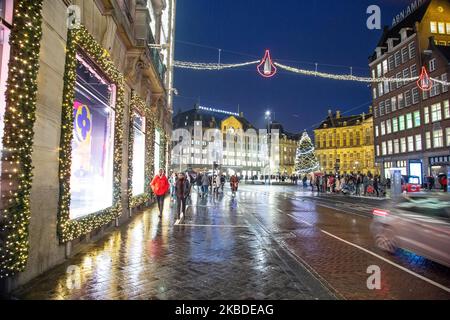 Weihnachtsdekoration im Stadtzentrum von Amsterdam in den Niederlanden mit Tausenden von Touristen und Besuchern, die einkaufen gehen, mit Taschen auf den Straßen spazieren gehen und Fotos mit den beleuchteten traditionellen Gebäuden und festlichen Installationen machen. 19. Dezember 2019 - Amsterdam, Niederlande (Foto von Nicolas Economou/NurPhoto) Stockfoto