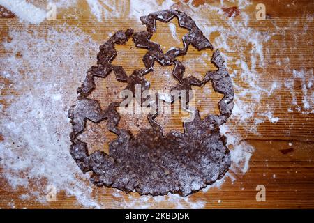 Backen von Weihnachtskandeln - Schneiden von Weihnachtskandeln aus hausgemachtem Teig in Sternformen - Zimtsterne Stockfoto