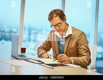 Wenn es wichtig ist, schreiben Sie es auf. Ein hübscher männlicher Designer, der an seinem Schreibtisch im Büro arbeitet. Stockfoto