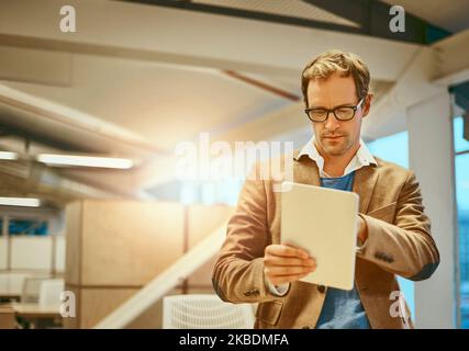 HES widmet sich dem Design. Ein hübscher männlicher Designer, der in seinem Büro an einem Tablet arbeitet. Stockfoto