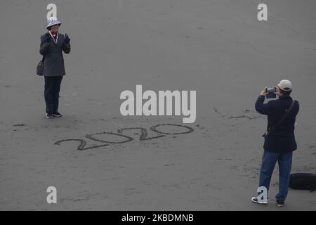 Ein Chinese fotografiert seine Frau mit 2020 im Sand geschriebenen Bildern während des Sonnenaufgangs am New Brighton Beach in Christchurch, Neuseeland am 01. Januar 2020.Â Â (Foto: Sanka Vidanagama/NurPhoto) Stockfoto