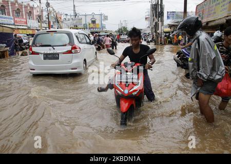 Die Bewohner überqueren die Überschwemmungen, die ihre Siedlungen überfluten, um am 1.. Januar 2020 in das Hochland im Cibitung Regency, West Java, zu fliehen. Der heftige Regen, der seit dem 31. Dezember 2019 mehr als 15 Stunden dauert, verursacht massive Überschwemmungen in der Hauptstadt Jakarta und in einigen Regionen und zwingt Tausende Einwohner zur Flucht. (Foto von Aditya Irawan/NurPhoto) Stockfoto
