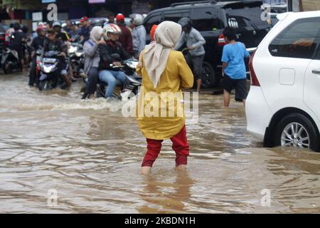 Die Bewohner überqueren die Überschwemmungen, die ihre Siedlungen überfluten, um am 1.. Januar 2020 in das Hochland im Cibitung Regency, West Java, zu fliehen. Der heftige Regen, der seit dem 31. Dezember 2019 mehr als 15 Stunden dauert, verursacht massive Überschwemmungen in der Hauptstadt Jakarta und in einigen Regionen und zwingt Tausende Einwohner zur Flucht. (Foto von Aditya Irawan/NurPhoto) Stockfoto