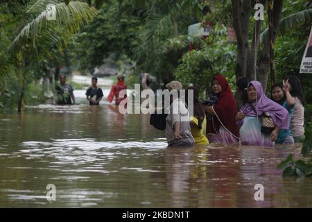 Die Bewohner überqueren die Überschwemmungen, die ihre Siedlungen überfluten, um am 1.. Januar 2020 in das Hochland im Cibitung Regency, West Java, zu fliehen. Der heftige Regen, der seit dem 31. Dezember 2019 mehr als 15 Stunden dauert, verursacht massive Überschwemmungen in der Hauptstadt Jakarta und in einigen Regionen und zwingt Tausende Einwohner zur Flucht. (Foto von Aditya Irawan/NurPhoto) Stockfoto