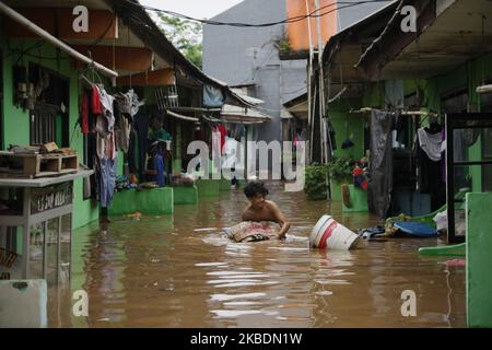 Die Bewohner überqueren die Überschwemmungen, die ihre Siedlungen überfluten, um am 1.. Januar 2020 in das Hochland im Cibitung Regency, West Java, zu fliehen. Der heftige Regen, der seit dem 31. Dezember 2019 mehr als 15 Stunden dauert, verursacht massive Überschwemmungen in der Hauptstadt Jakarta und in einigen Regionen und zwingt Tausende Einwohner zur Flucht. (Foto von Aditya Irawan/NurPhoto) Stockfoto