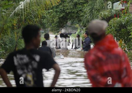 Die Bewohner überqueren die Überschwemmungen, die ihre Siedlungen überfluten, um am 1.. Januar 2020 in das Hochland im Cibitung Regency, West Java, zu fliehen. Der heftige Regen, der seit dem 31. Dezember 2019 mehr als 15 Stunden dauert, verursacht massive Überschwemmungen in der Hauptstadt Jakarta und in einigen Regionen und zwingt Tausende Einwohner zur Flucht. (Foto von Aditya Irawan/NurPhoto) Stockfoto