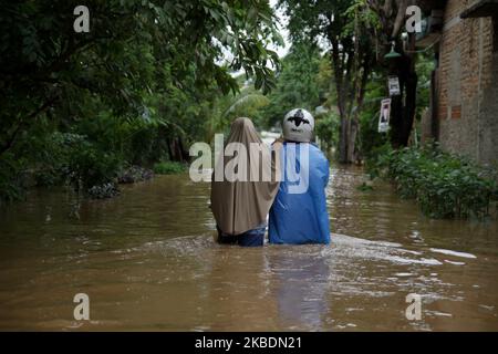 Die Bewohner überqueren die Überschwemmungen, die ihre Siedlungen überfluten, um am 1.. Januar 2020 in das Hochland im Cibitung Regency, West Java, zu fliehen. Der heftige Regen, der seit dem 31. Dezember 2019 mehr als 15 Stunden dauert, verursacht massive Überschwemmungen in der Hauptstadt Jakarta und in einigen Regionen und zwingt Tausende Einwohner zur Flucht. (Foto von Aditya Irawan/NurPhoto) Stockfoto