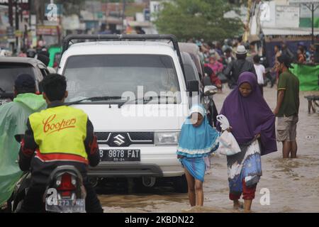 Die Bewohner überqueren die Überschwemmungen, die ihre Siedlungen überfluten, um am 1.. Januar 2020 in das Hochland im Cibitung Regency, West Java, zu fliehen. Der heftige Regen, der seit dem 31. Dezember 2019 mehr als 15 Stunden dauert, verursacht massive Überschwemmungen in der Hauptstadt Jakarta und in einigen Regionen und zwingt Tausende Einwohner zur Flucht. (Foto von Aditya Irawan/NurPhoto) Stockfoto