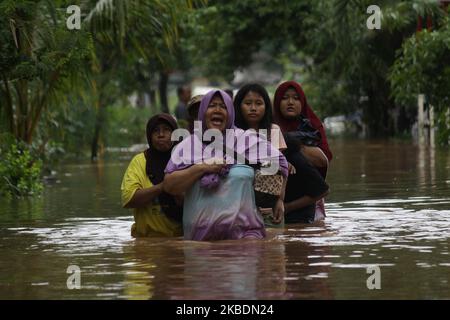 Die Bewohner überqueren die Überschwemmungen, die ihre Siedlungen überfluten, um am 1.. Januar 2020 in das Hochland im Cibitung Regency, West Java, zu fliehen. Der heftige Regen, der seit dem 31. Dezember 2019 mehr als 15 Stunden dauert, verursacht massive Überschwemmungen in der Hauptstadt Jakarta und in einigen Regionen und zwingt Tausende Einwohner zur Flucht. (Foto von Aditya Irawan/NurPhoto) Stockfoto