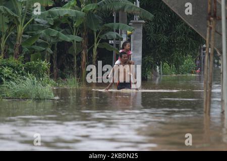 Die Bewohner überqueren die Überschwemmungen, die ihre Siedlungen überfluten, um am 1.. Januar 2020 in das Hochland im Cibitung Regency, West Java, zu fliehen. Der heftige Regen, der seit dem 31. Dezember 2019 mehr als 15 Stunden dauert, verursacht massive Überschwemmungen in der Hauptstadt Jakarta und in einigen Regionen und zwingt Tausende Einwohner zur Flucht. (Foto von Aditya Irawan/NurPhoto) Stockfoto