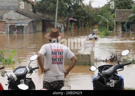 Die Bewohner überqueren die Überschwemmungen, die ihre Siedlungen überfluten, um am 1.. Januar 2020 in das Hochland im Cibitung Regency, West Java, zu fliehen. Der heftige Regen, der seit dem 31. Dezember 2019 mehr als 15 Stunden dauert, verursacht massive Überschwemmungen in der Hauptstadt Jakarta und in einigen Regionen und zwingt Tausende Einwohner zur Flucht. (Foto von Aditya Irawan/NurPhoto) Stockfoto