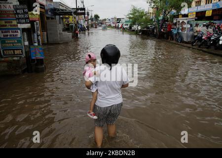 Die Bewohner überqueren die Überschwemmungen, die ihre Siedlungen überfluten, um am 1.. Januar 2020 in das Hochland im Cibitung Regency, West Java, zu fliehen. Der heftige Regen, der seit dem 31. Dezember 2019 mehr als 15 Stunden dauert, verursacht massive Überschwemmungen in der Hauptstadt Jakarta und in einigen Regionen und zwingt Tausende Einwohner zur Flucht. (Foto von Aditya Irawan/NurPhoto) Stockfoto