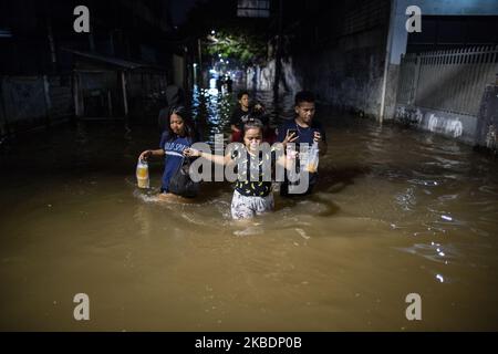 Am 02. Januar 2020 waten die Bewohner durch ein überflutetes Gebiet auf der Hauptstraße in West Jakarta, Indonesien. Die Überschwemmungen durch starken Regen ließen mindestens 21 Menschen sterben und Zehntausende von Menschen aus ihren Häusern vertrieben, während sich die Stadt auf die anhaltenden Regenfälle vorbereitet. (Foto von Afriadi Hikmal/NurPhoto) Stockfoto