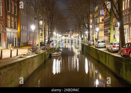 Grachten in Amsterdam wie Amstel mit typischen traditionellen alten niederländischen Architektur Häuser beleuchtet und Hausboote am Abend und Nacht mit schönen Wasserspiegelungen und Stadtlichter, Holland, Niederlande. Amsterdam ist ein Finanzzentrum, aber auch eine der meistbesuchten Städte Europas, die Millionen von Touristen auf der ganzen Welt anzieht, wobei der Tourismus eine wichtige Rolle in der lokalen Wirtschaft spielt, obwohl es Stimmen gegen diese touristische Entwicklung gibt. (Foto von Nicolas Economou/NurPhoto) Stockfoto