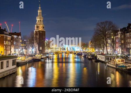 Grachten in Amsterdam wie Amstel mit typischen traditionellen alten niederländischen Architektur Häuser beleuchtet und Hausboote am Abend und Nacht mit schönen Wasserspiegelungen und Stadtlichter, Holland, Niederlande. Amsterdam ist ein Finanzzentrum, aber auch eine der meistbesuchten Städte Europas, die Millionen von Touristen auf der ganzen Welt anzieht, wobei der Tourismus eine wichtige Rolle in der lokalen Wirtschaft spielt, obwohl es Stimmen gegen diese touristische Entwicklung gibt. (Foto von Nicolas Economou/NurPhoto) Stockfoto